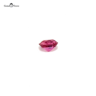 A soft pink padparadscha sapphire in a cushion cut, laying against a white background.